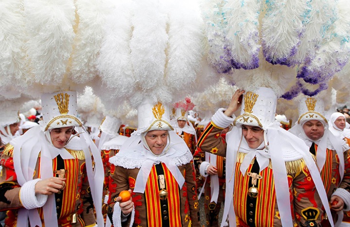 The Gilles of Binche hold oranges as they parade during the carnival